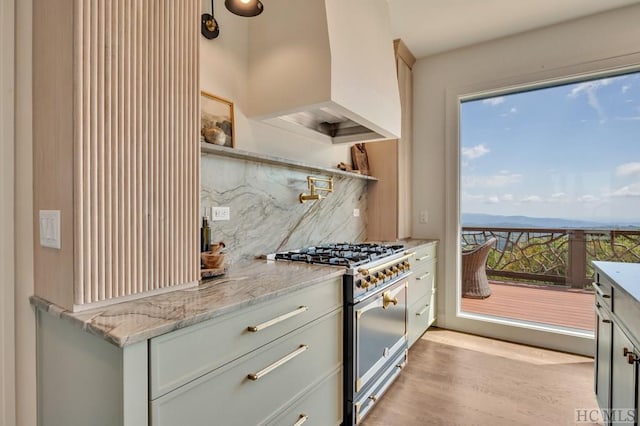 kitchen featuring premium range hood, a healthy amount of sunlight, high end stove, and backsplash