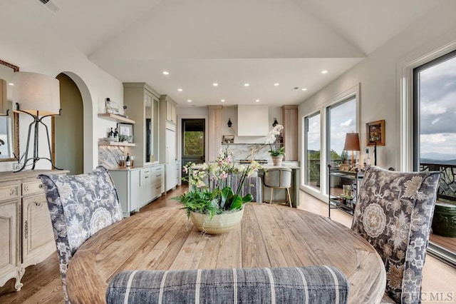 dining room with light hardwood / wood-style flooring and vaulted ceiling