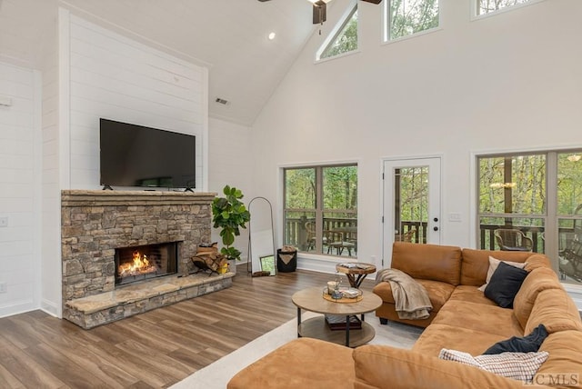 living room featuring ceiling fan, hardwood / wood-style floors, a fireplace, and high vaulted ceiling