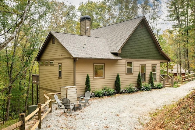 back of house featuring roof with shingles and a chimney