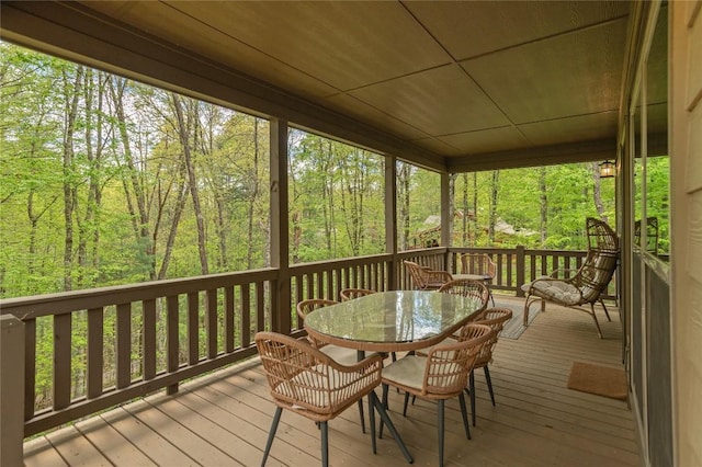 sunroom / solarium with outdoor dining space and a forest view
