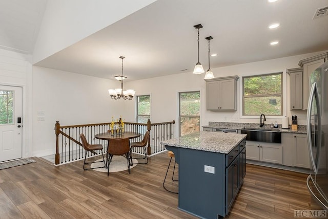 kitchen featuring sink, a center island, pendant lighting, and stainless steel fridge