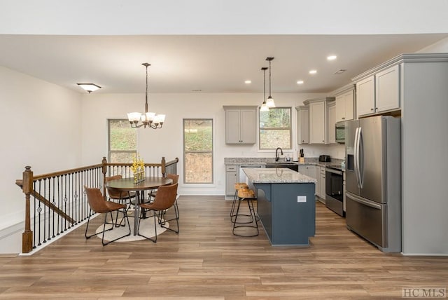 kitchen with pendant lighting, a kitchen island, gray cabinetry, and appliances with stainless steel finishes