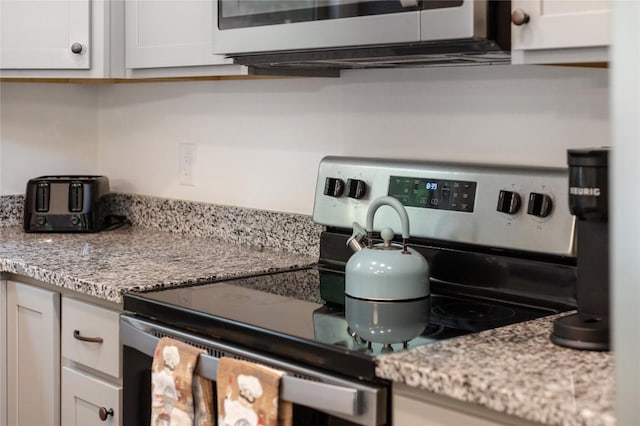 kitchen featuring appliances with stainless steel finishes, white cabinetry, and light stone counters