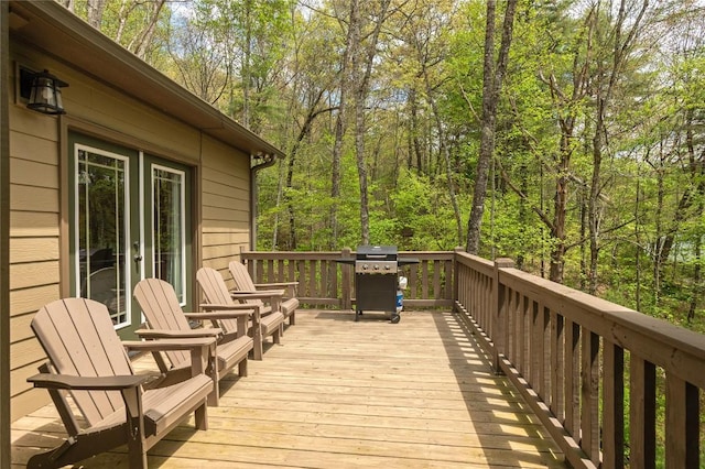 wooden deck featuring grilling area, a wooded view, and french doors