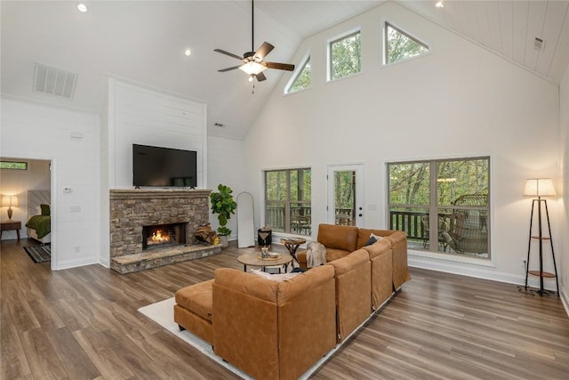 living area featuring high vaulted ceiling, a ceiling fan, wood finished floors, a fireplace, and baseboards
