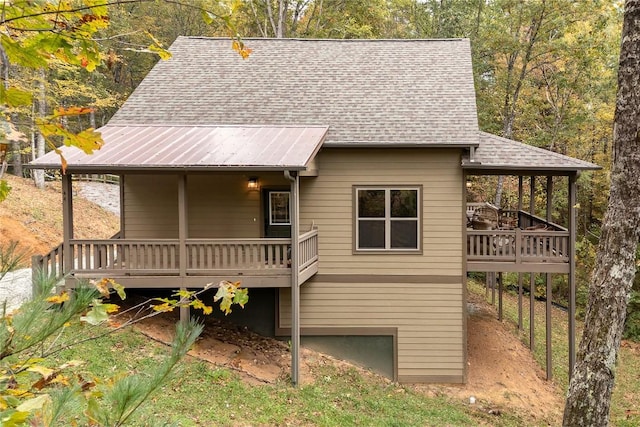 back of house featuring a shingled roof and a deck