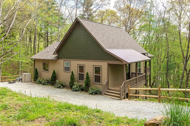 view of front facade with covered porch, fence, and a shingled roof