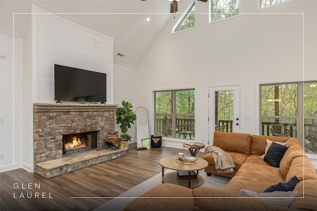 living area with high vaulted ceiling, wood finished floors, ceiling fan, a fireplace, and recessed lighting