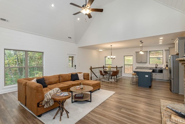 living room featuring sink, ceiling fan with notable chandelier, high vaulted ceiling, and light hardwood / wood-style floors