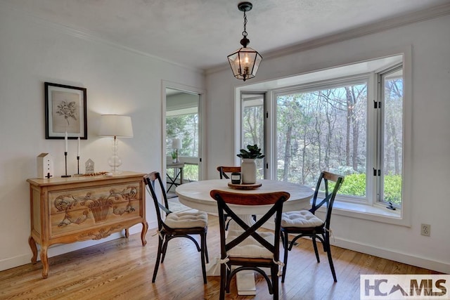 dining room with ornamental molding, baseboards, light wood-type flooring, and a chandelier