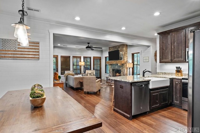 kitchen with appliances with stainless steel finishes, dark brown cabinets, and kitchen peninsula