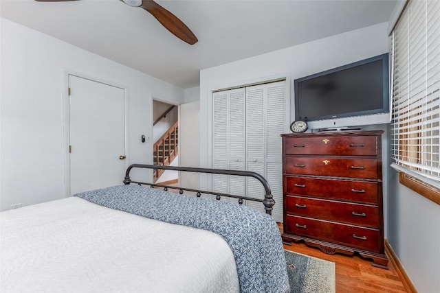 bedroom featuring a closet, ceiling fan, baseboards, and wood finished floors