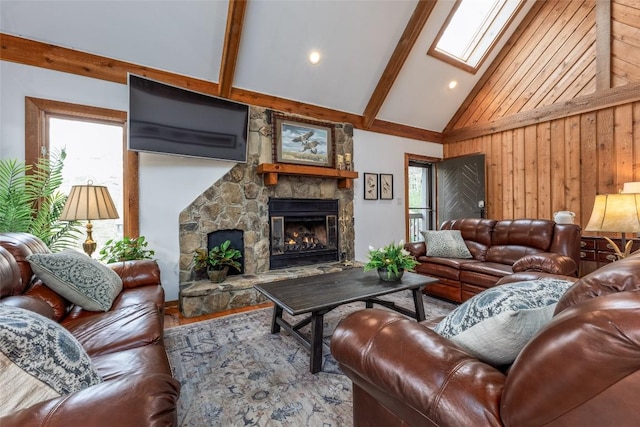 living area with high vaulted ceiling, a fireplace, a skylight, and beam ceiling