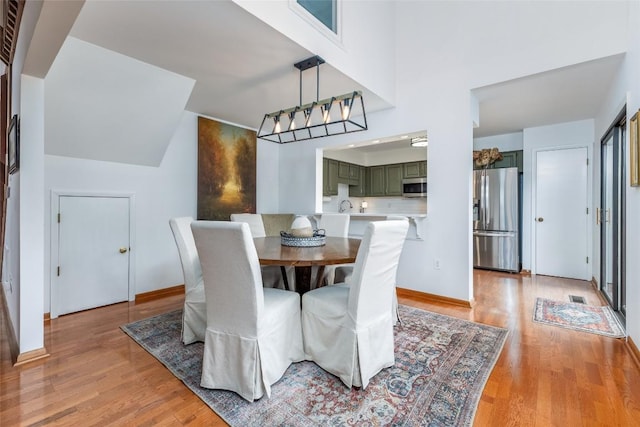 dining space with light wood finished floors, visible vents, and baseboards