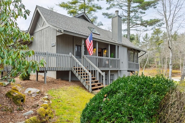 back of property featuring roof with shingles, a chimney, and stairs