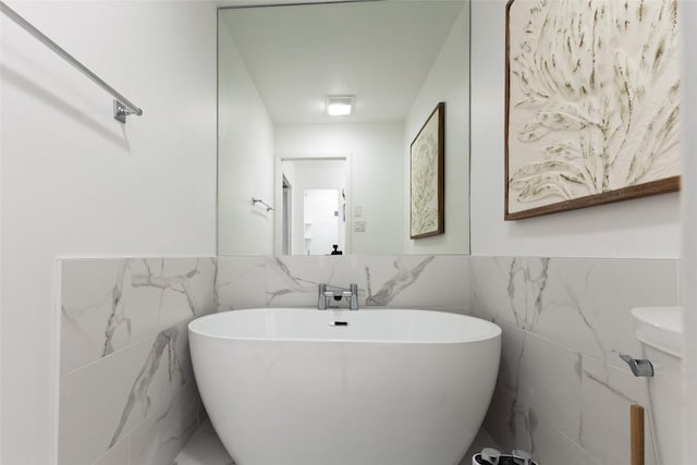 bathroom with a freestanding tub, tile walls, and wainscoting