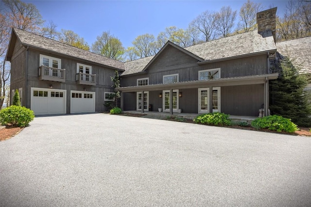 212 Ivorybill Way, Cashiers, NC 28717 - view of front of house with a balcony, french doors, a chimney, an attached garage, and driveway