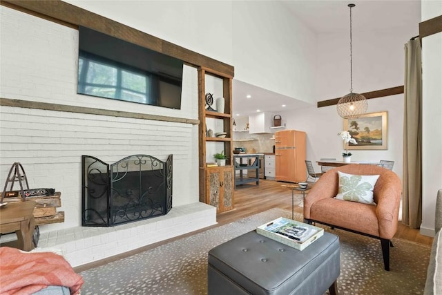 living room featuring a towering ceiling, wood finished floors, and a fireplace
