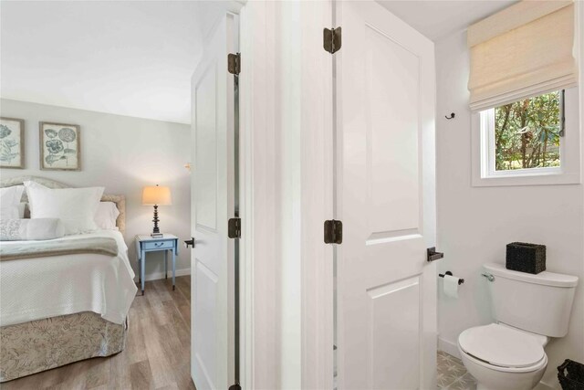 bathroom featuring baseboards, wood finished floors, and toilet
