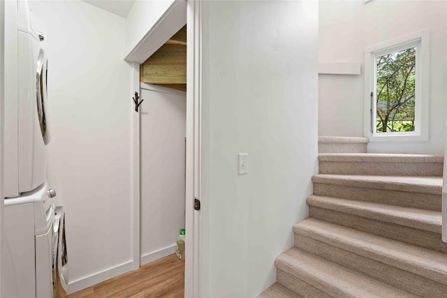stairway featuring stacked washer and dryer and wood finished floors