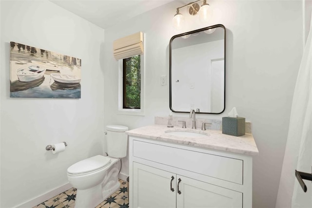 bathroom with baseboards, vanity, and toilet