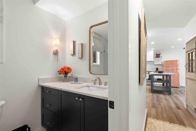 bathroom featuring vanity, toilet, recessed lighting, wood finished floors, and backsplash