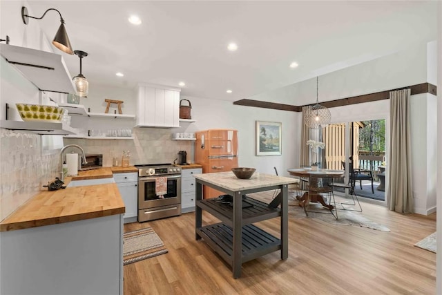kitchen featuring open shelves, stainless steel range with electric stovetop, a sink, light wood finished floors, and butcher block counters
