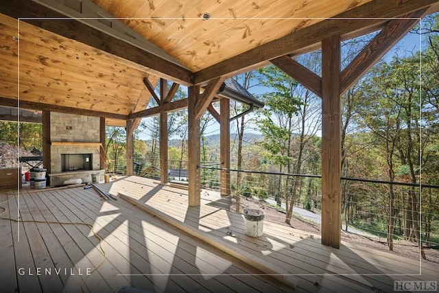 wooden deck featuring an outdoor stone fireplace