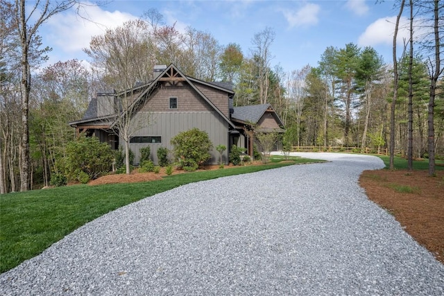 view of property exterior featuring board and batten siding, a yard, a chimney, and gravel driveway
