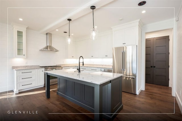 kitchen with white cabinetry, wall chimney exhaust hood, a kitchen island with sink, and premium appliances