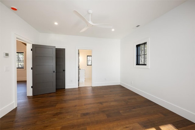 unfurnished bedroom featuring multiple windows, dark hardwood / wood-style floors, ceiling fan, and ensuite bath