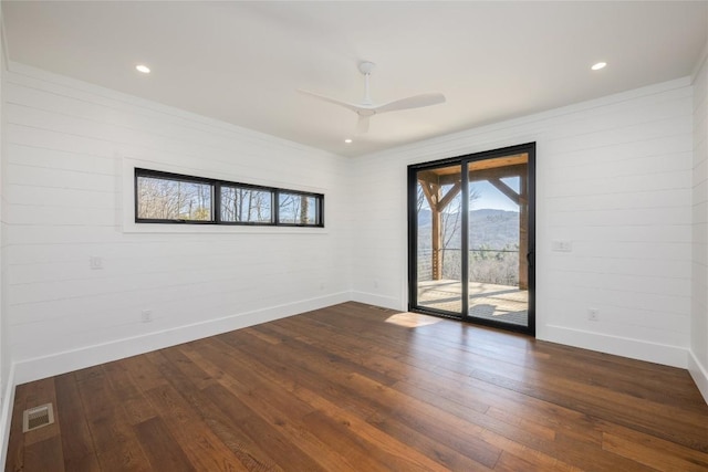 empty room with baseboards, a ceiling fan, dark wood-type flooring, and visible vents