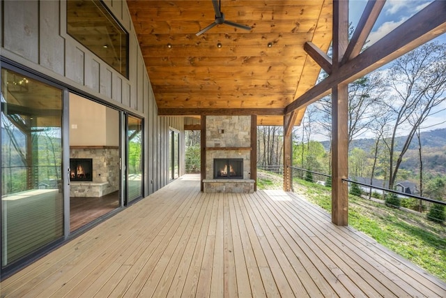wooden terrace featuring an outdoor stone fireplace and a mountain view