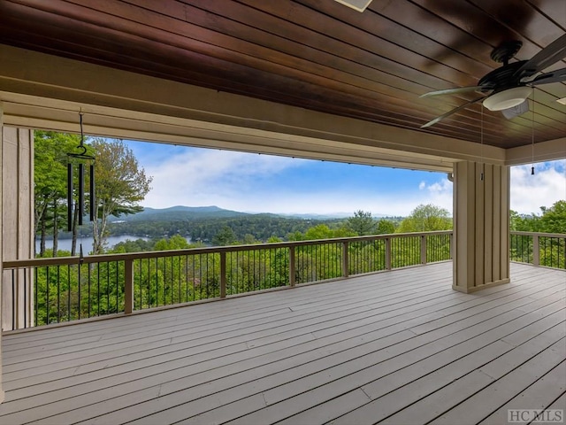 wooden terrace with a water and mountain view and ceiling fan