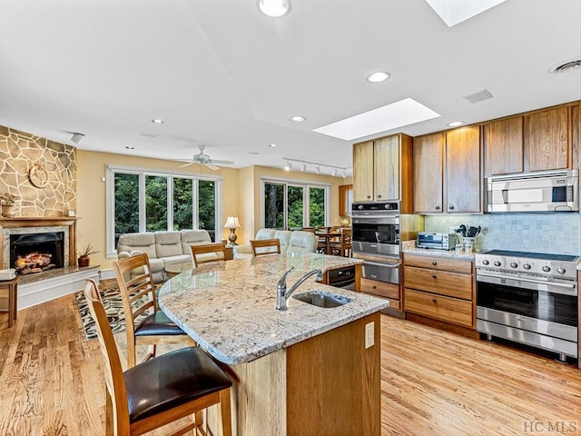 kitchen with sink, a breakfast bar area, backsplash, a skylight, and stainless steel appliances