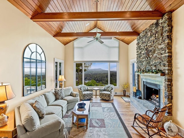 living room with ceiling fan, a healthy amount of sunlight, a stone fireplace, and light wood-type flooring