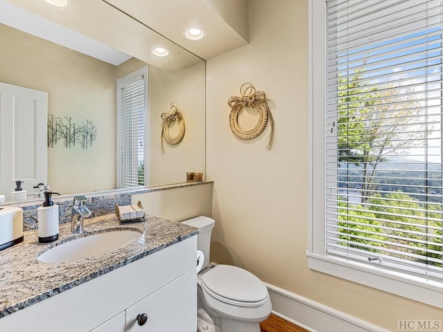 bathroom featuring a healthy amount of sunlight, vanity, and toilet