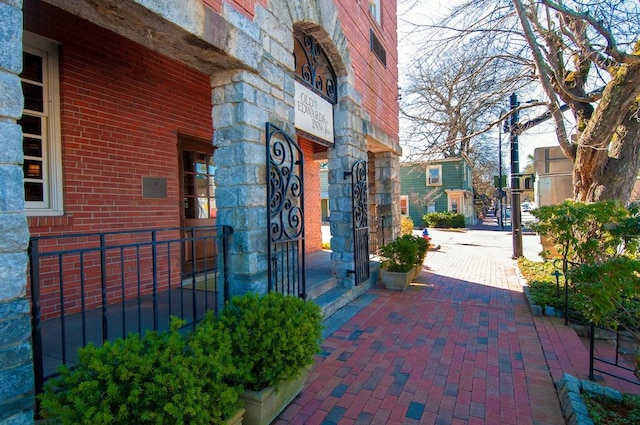 view of exterior entry with stone siding, brick siding, and fence
