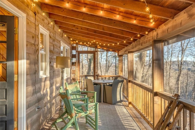 unfurnished sunroom with vaulted ceiling with beams, wood ceiling, plenty of natural light, and rail lighting