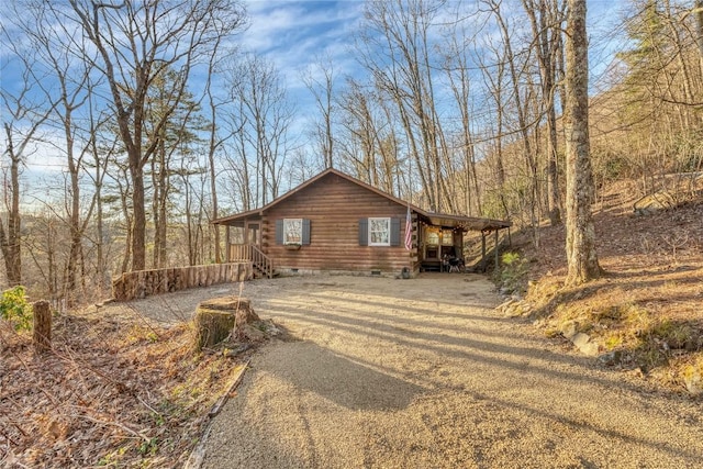 view of front facade featuring crawl space, driveway, and log siding