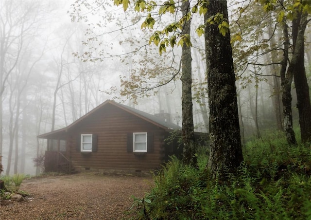 view of side of home with crawl space and log siding