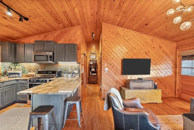 kitchen featuring appliances with stainless steel finishes, wooden ceiling, gray cabinets, a kitchen breakfast bar, and light wood-style floors
