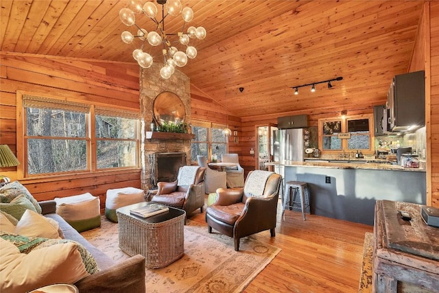 living area with a stone fireplace, wooden ceiling, wooden walls, light wood-type flooring, and track lighting