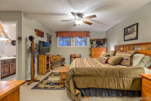 bedroom with a textured ceiling, light carpet, connected bathroom, and ceiling fan