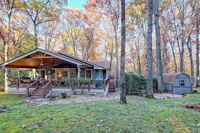 view of front facade with a shed, ceiling fan, and a front lawn