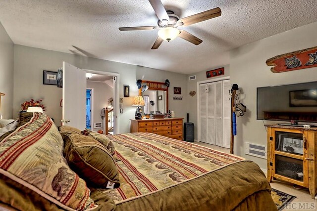 bedroom featuring ceiling fan, carpet flooring, a closet, and a textured ceiling