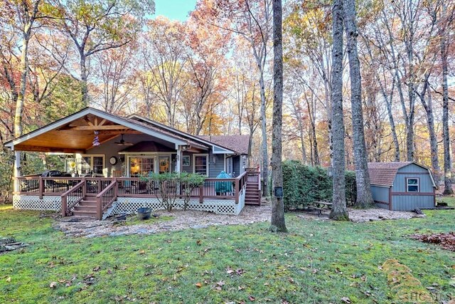 view of front of property with a shed, a wooden deck, a front yard, and ceiling fan