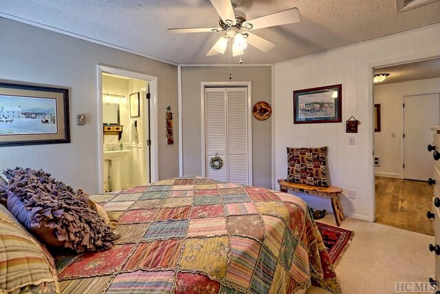 carpeted bedroom with ensuite bath, a textured ceiling, ceiling fan, and a closet