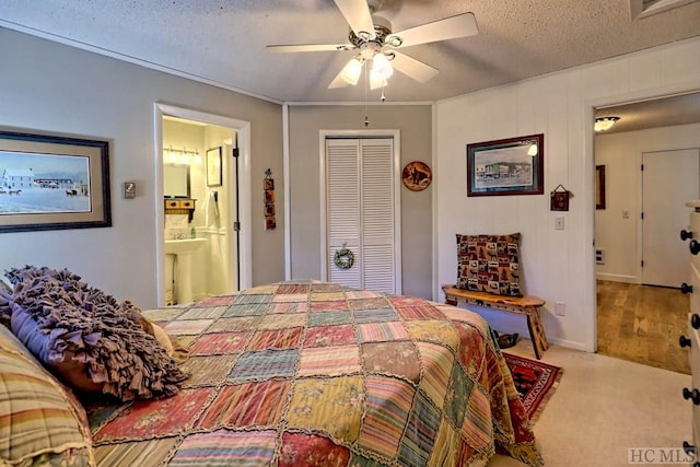 carpeted bedroom with ensuite bath, a closet, ceiling fan, and a textured ceiling